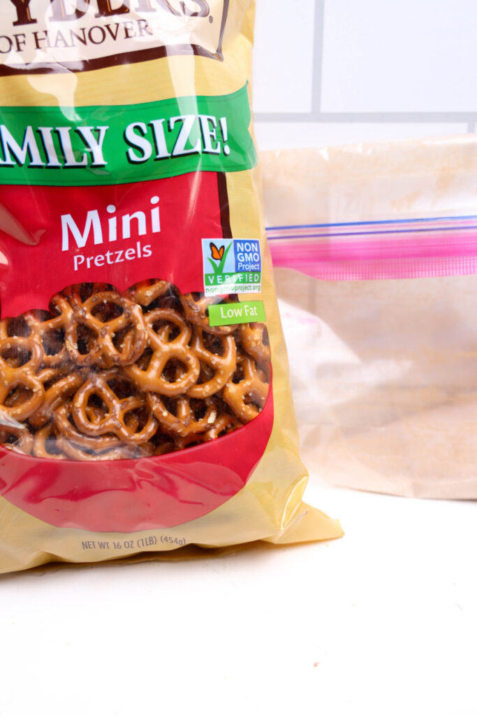 A family size bag of mini pretzels sits next to a partially visible resealable plastic bag containing a light brown powder.