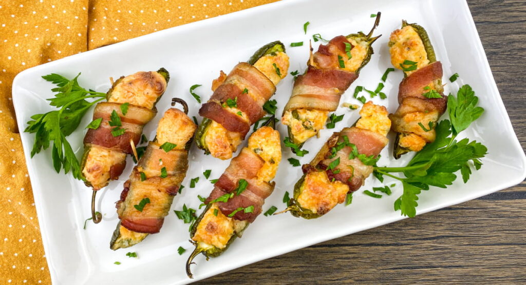 A plate of jalapeno poppers wrapped in bacon.