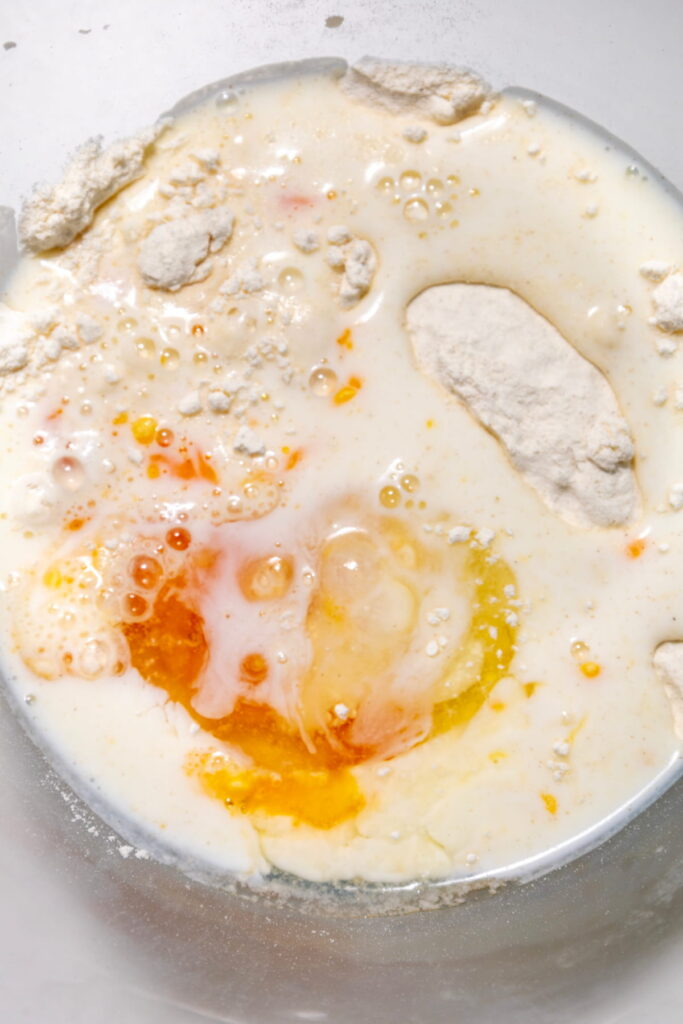 A close-up of raw baking ingredients in a bowl, including flour, eggs, and milk, before mixing.